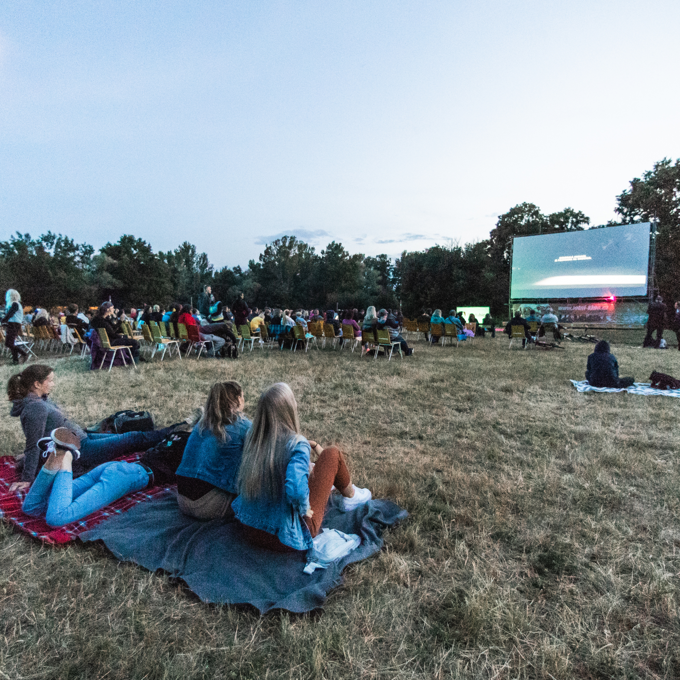 A group of friends watching a film at an outdoor cinema.